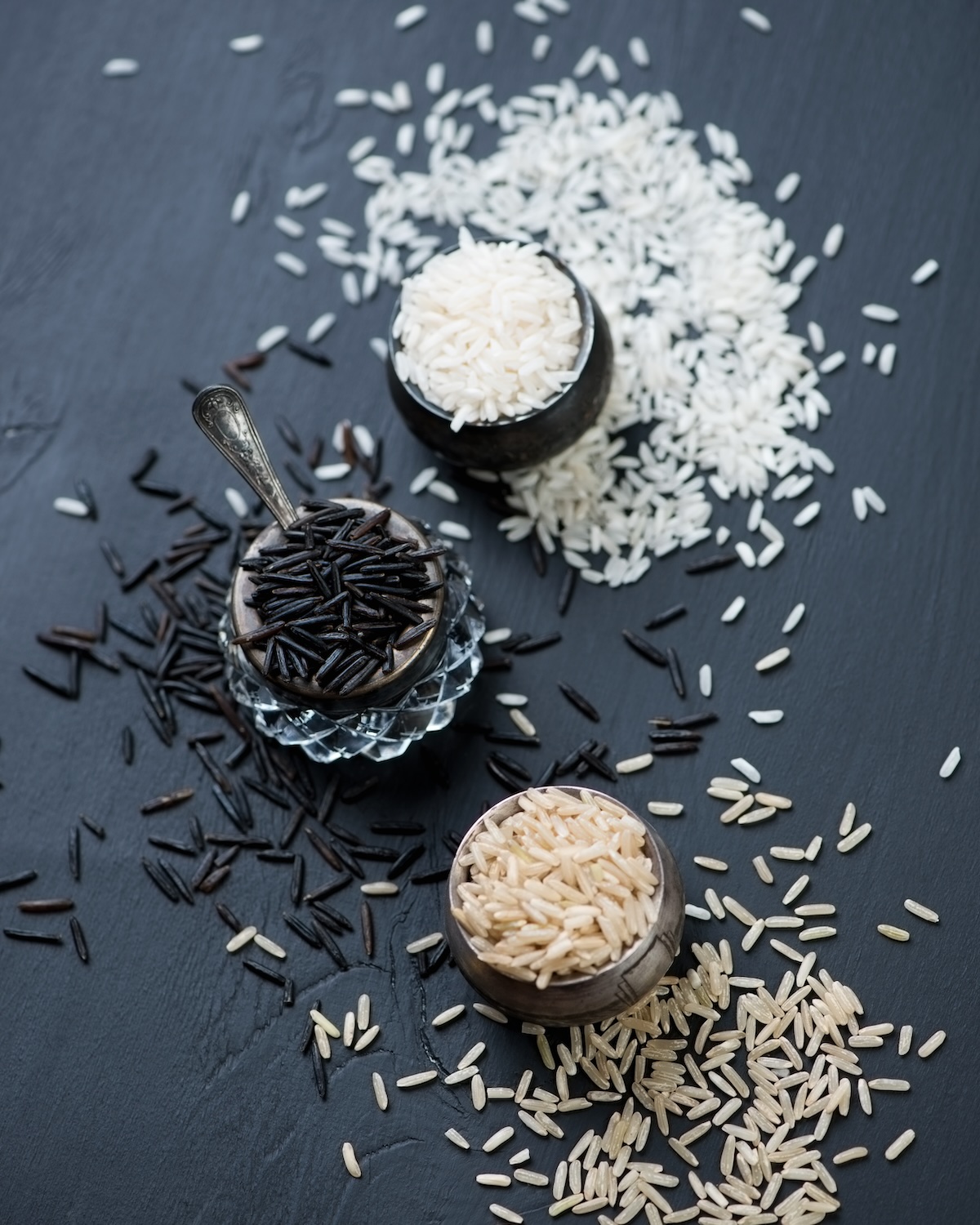 Variety of raw rice, black wooden background, view from above