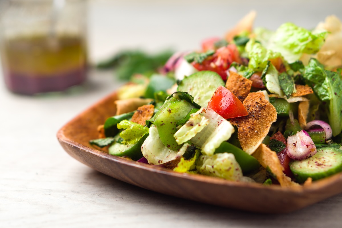 Salade fattouche servie avec herbes fraîches, tomates, concombre et pain pita grillé