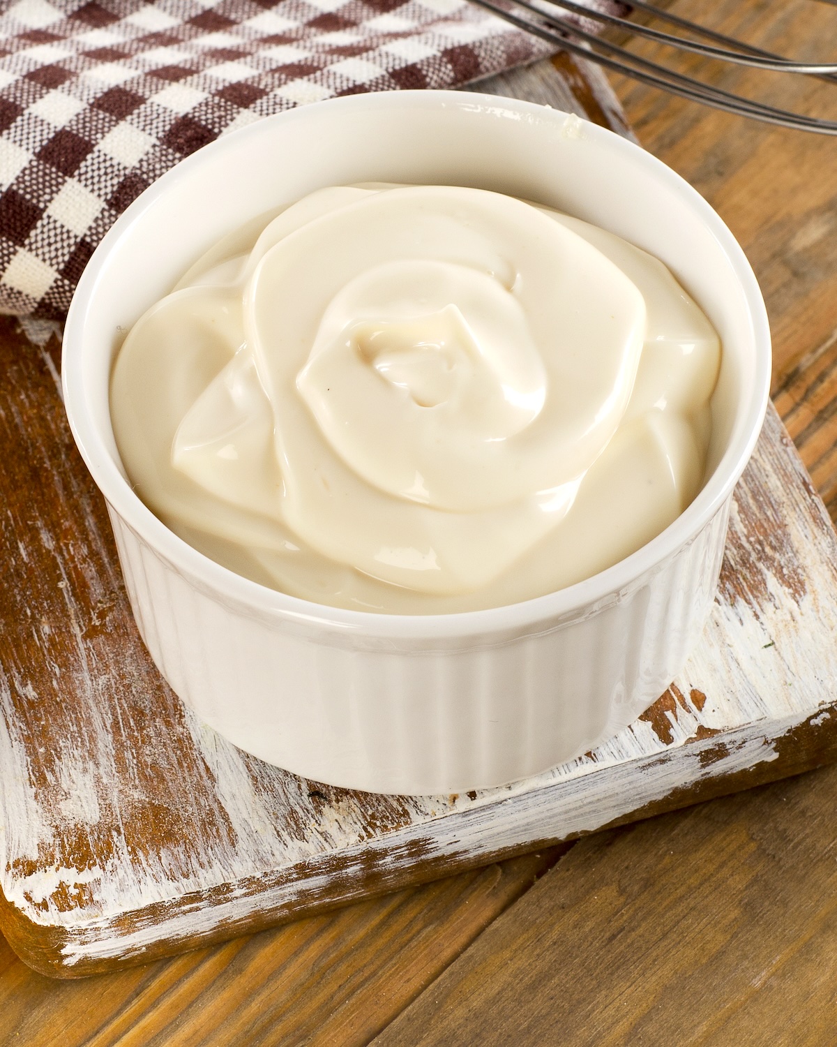 Mayonnaise in a bowl on wooden background.