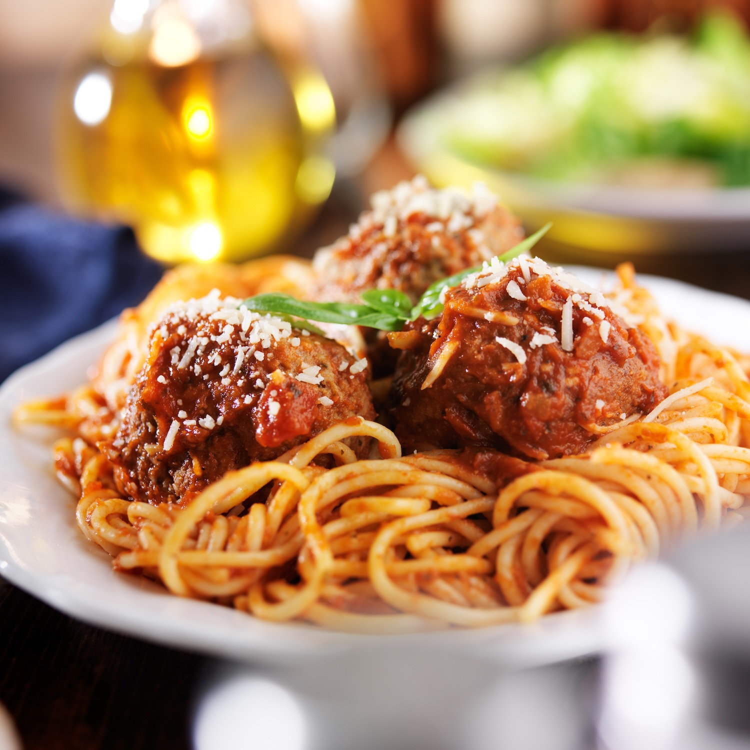 Italian spaghetti and meatballs with salad in background 