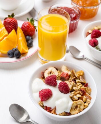 Healthy Breakfast Meal - Bowl of Fruit, Oat and Nut Granola with Yogurt and Raspberries