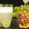 The Peruvian cocktail, Pisco Sour with the Peruvian snack, roasted corn, called cancha and grapes, limes, Pisco Sour and habas (roasted beans) in the background (Selective Focus, Focus on the front)
