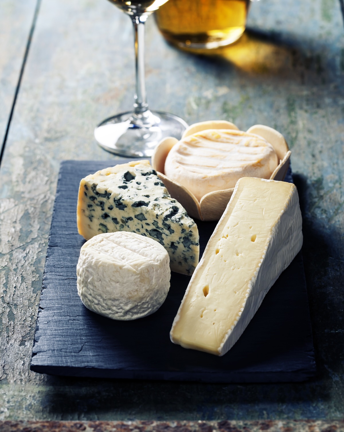 Various types of cheese and white wine on wooden background