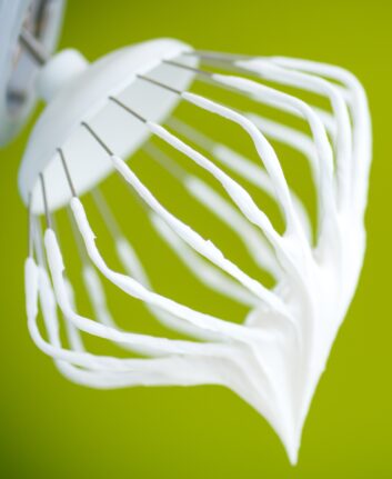 whipped cream with a metal whisk on a green background
