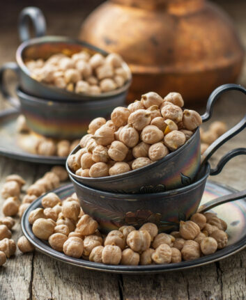 Vintage silver cup filled with dry chickpeas on a dark wooden background. selective Focus