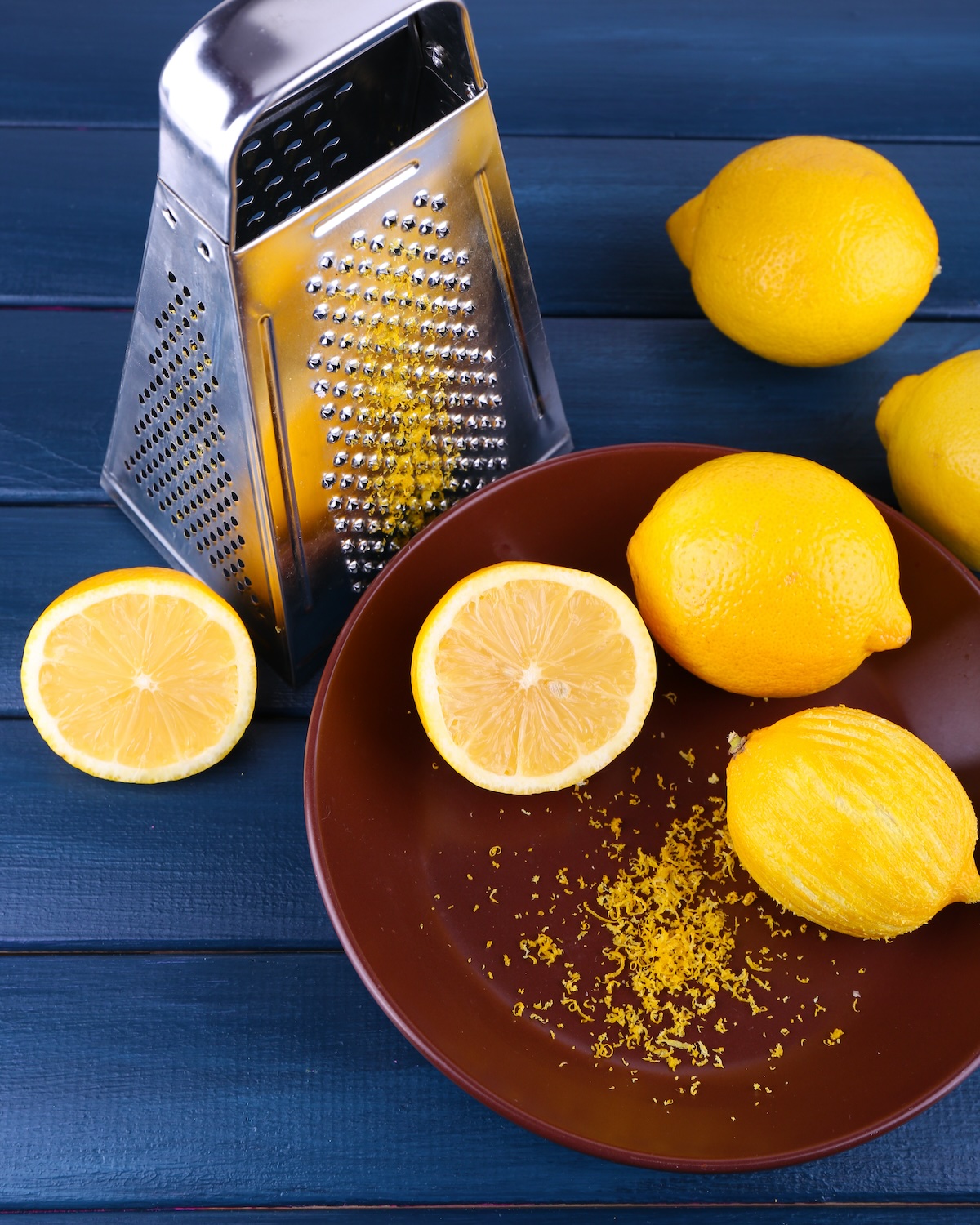 Lemons,On,Plate,And,Grater,On,Dark,Blue,Wooden,Background