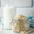 Lait d'avoine dans une bouteille et flocons d'avoine dans un pot en verre