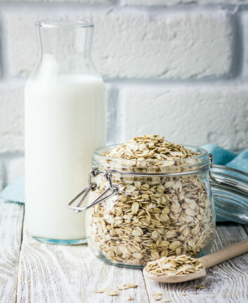 Lait d'avoine dans une bouteille et flocons d'avoine dans un pot en verre