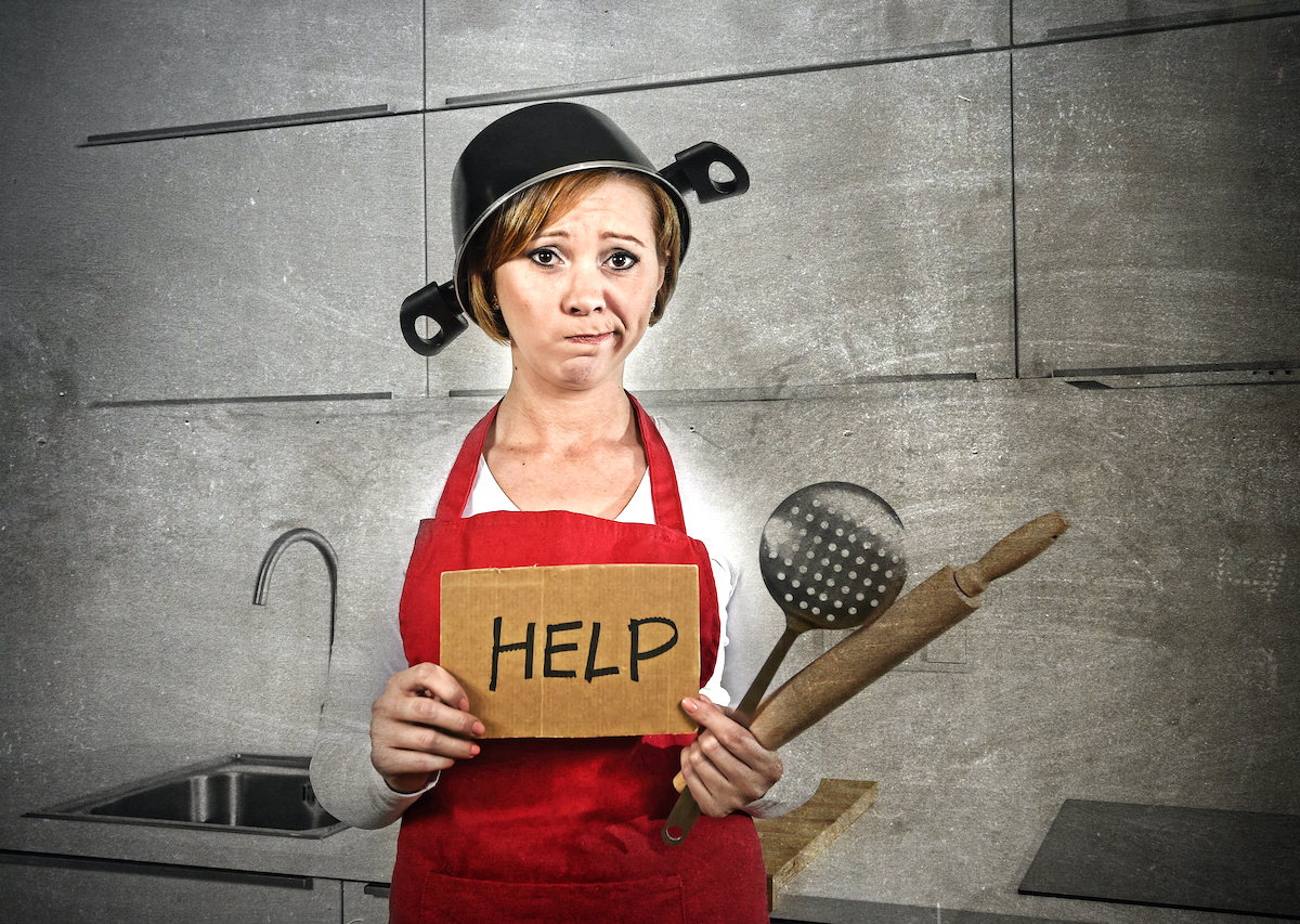 sweet cook woman confused and frustrated face expression wearing red apron asking for help holding rolling pin and cooking pot on the head at home kitchen in domestic stress and lifestyle concept