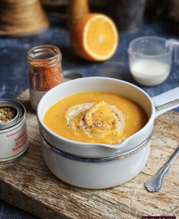 Velouté de carottes, orange et gingembre dans une casserole blanche, prêt à servir