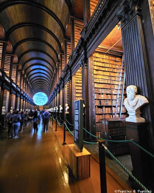 La Long Room de Trinity College, galerie de bois sombre, rangées de livres anciens et voûte impressionnante