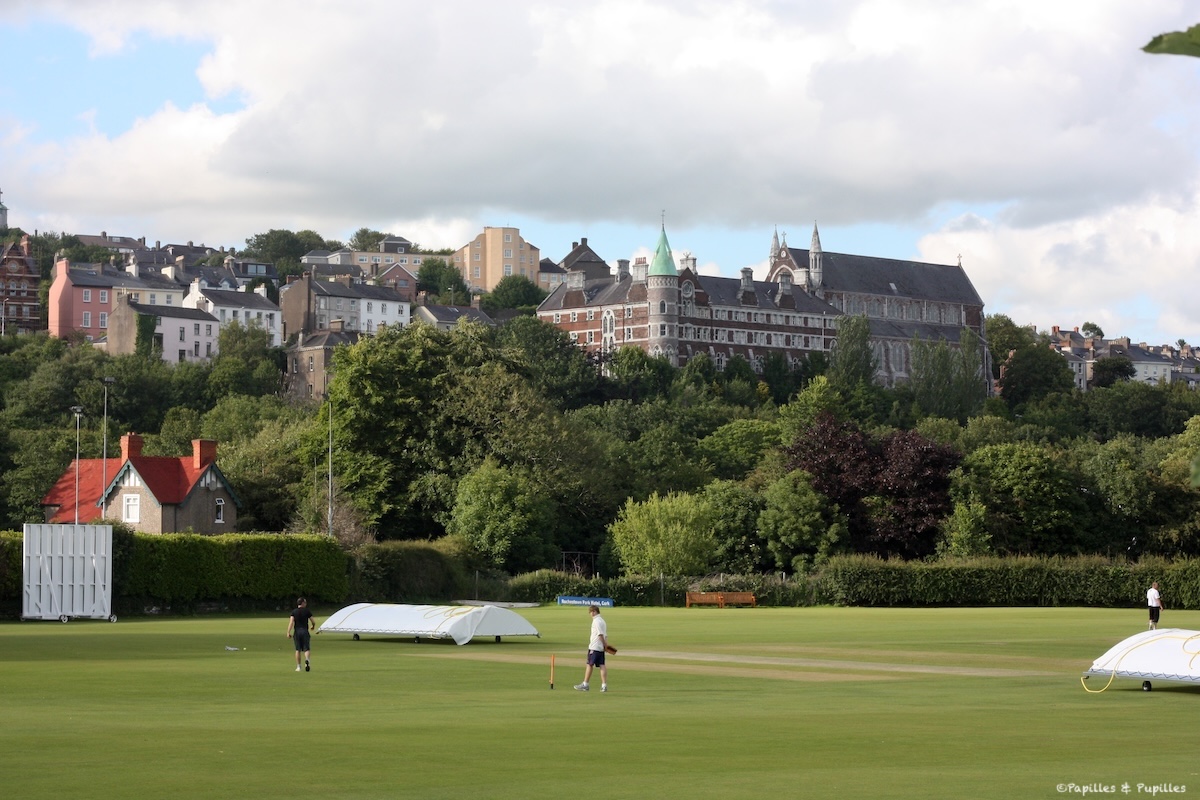 Terrain de cricket du Mardyke à Cork avec St Fin Barre’s Cathedral en arrière-plan sous un ciel nuageux