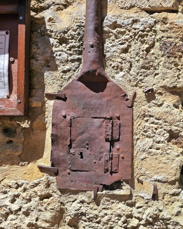 Ancien élément métallique accroché à un mur de pierre dans le village de Belvès