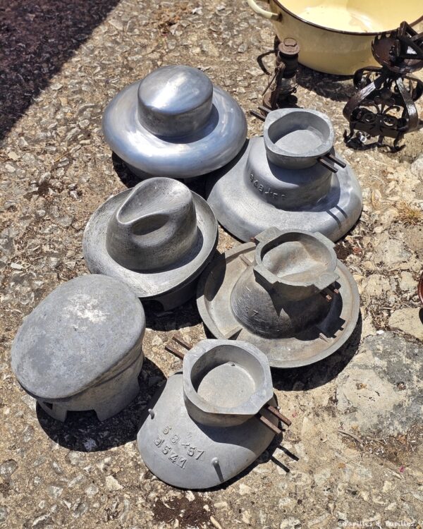 Moules anciens en métal exposés au soleil sur une brocante à Monpazier