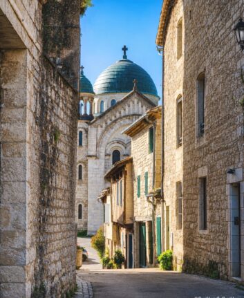 Rue en pente de Castelnau-Montratier avec l’église Saint-Martin et sa coupole bleue en arrière-plan