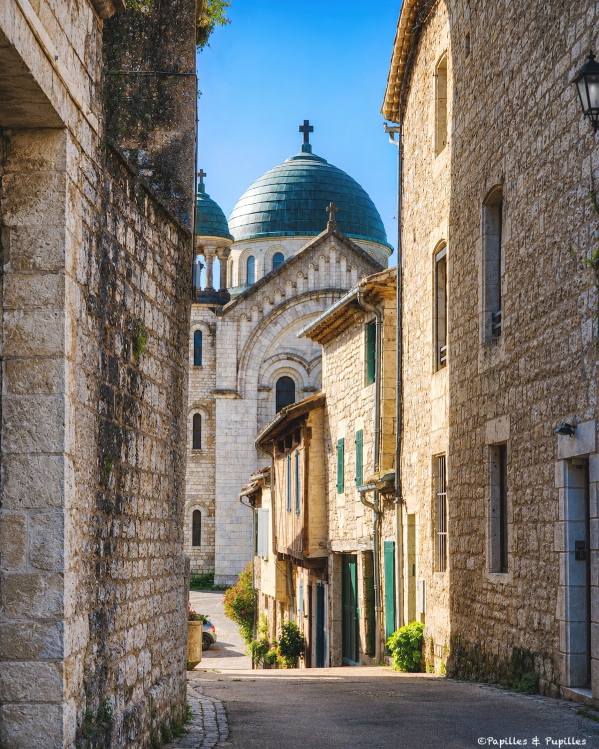 Rue en pente de Castelnau-Montratier avec l’église Saint-Martin et sa coupole bleue en arrière-plan