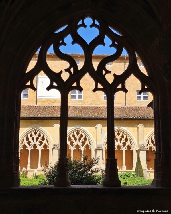 Cloître de Cadouin vu à travers une arcade gothique ajourée
