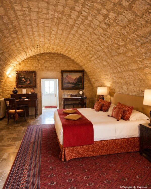 Chambre voûtée en pierre au Domaine de Saint-Géry avec grand lit et tapis rouge