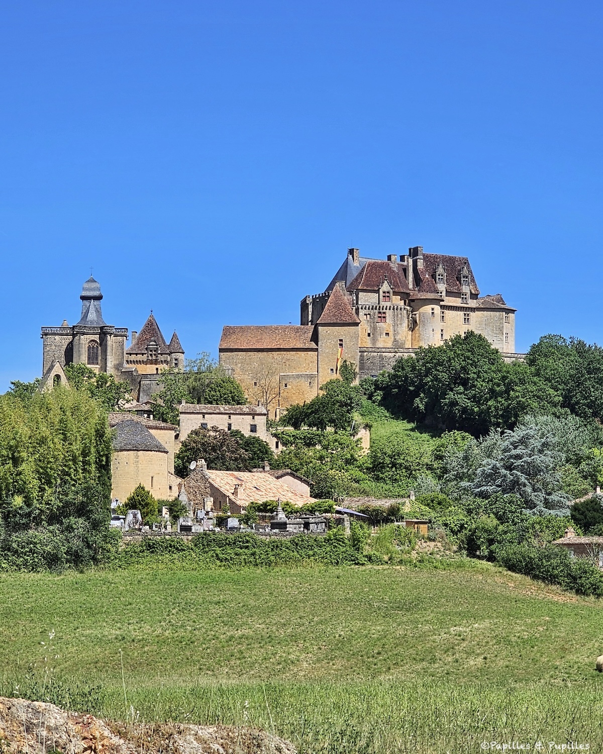 Château de Biron dominant le village et la campagne du Périgord sous un grand ciel bleu
