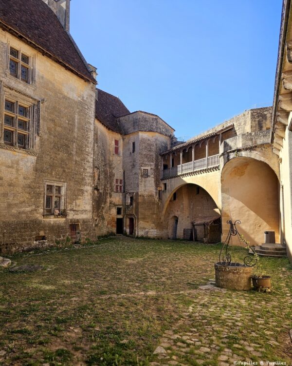 Cour intérieure du Château de Biron avec puits, façades anciennes et galerie couverte