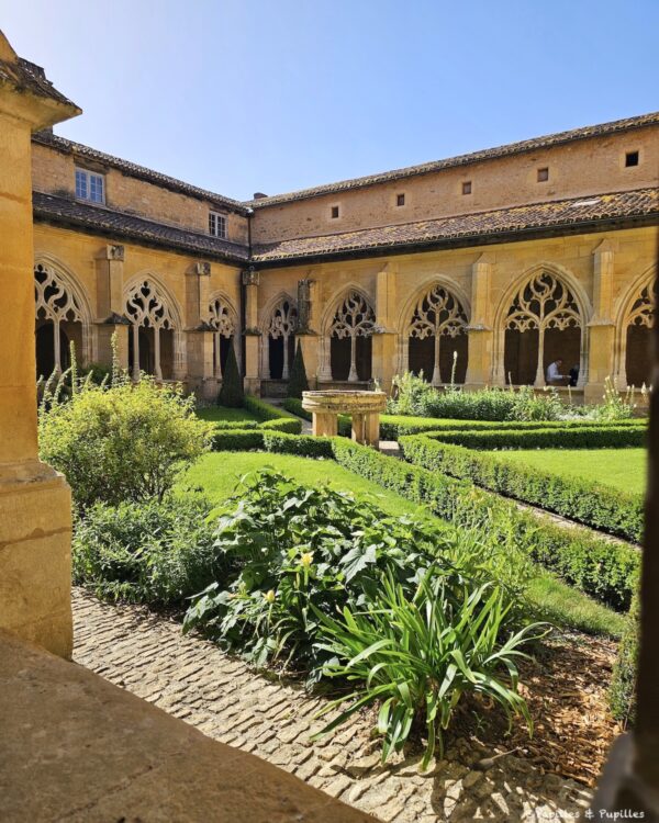 Jardin intérieur du cloître de Cadouin avec haies taillées, puits et arcades gothiques