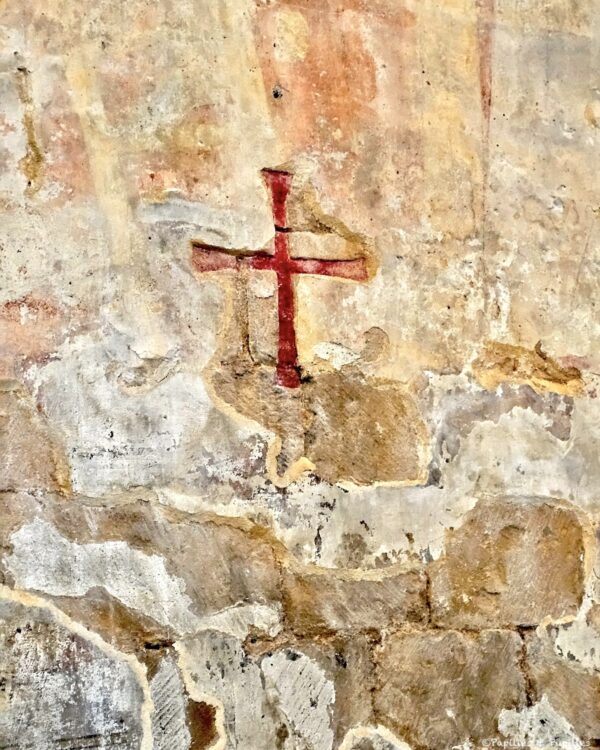 Croix ancienne peinte sur un mur de pierre dans l'église de Cadouin