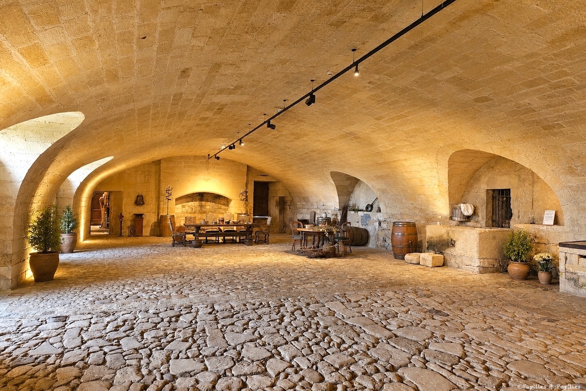 Grande cuisine voûtée du Château de Biron avec sol pavé, foyers et mobilier ancien