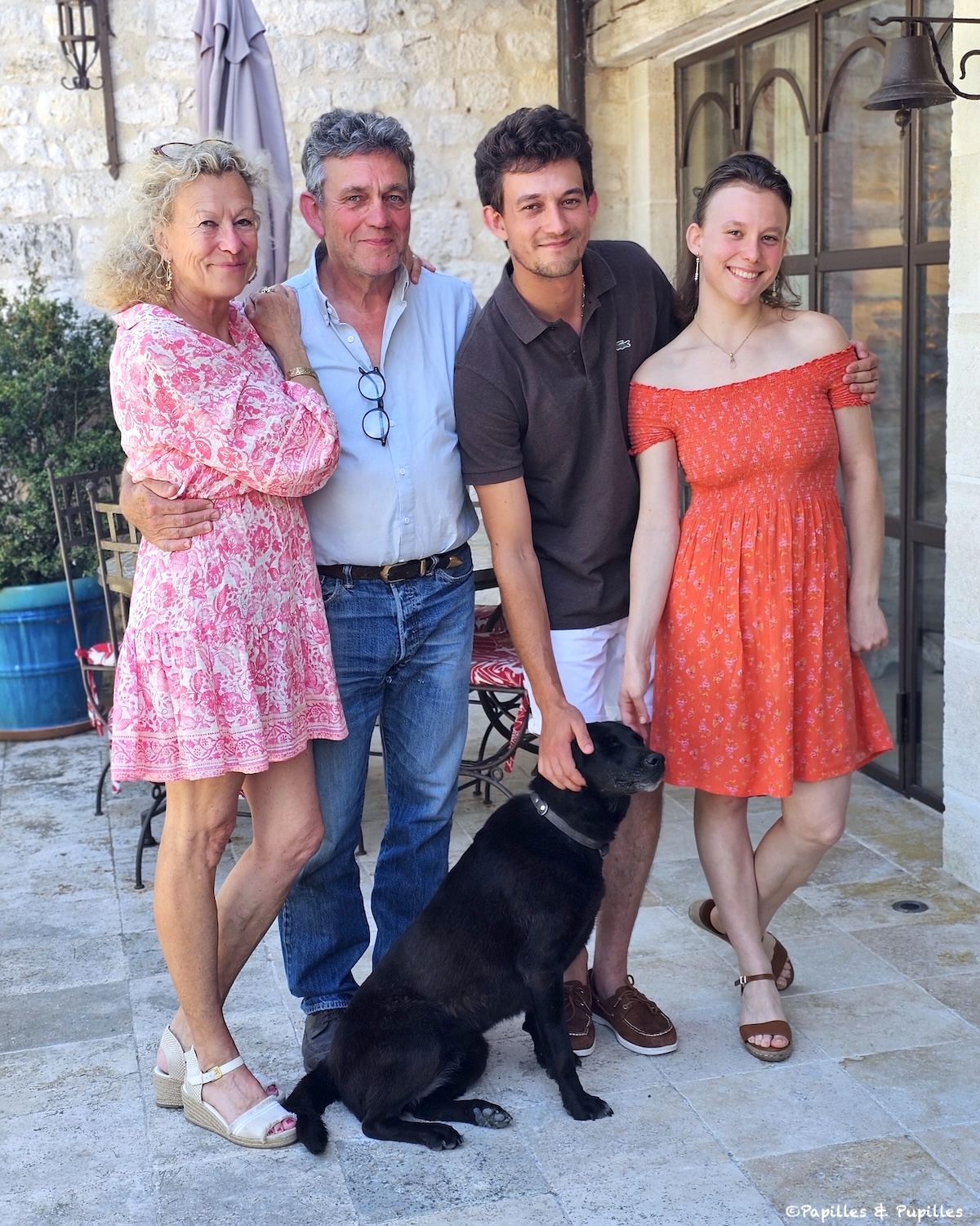 Famille Duler posant dans la cour du Domaine de Saint-Géry avec un chien noir