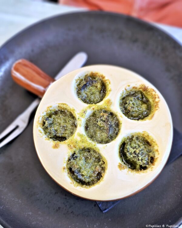 Six escargots en persillade servis dans un plat à escargots