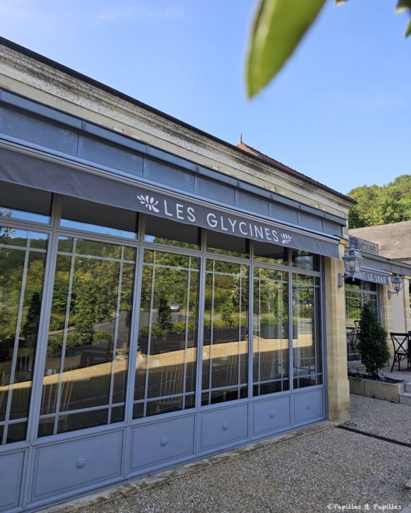 Façade vitrée de l’hôtel Les Glycines avec store gris et grande terrasse
