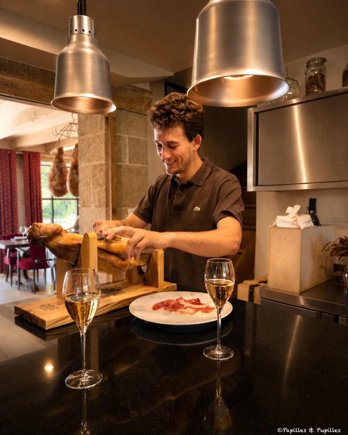 Découpe d’un jambon affiné à la Maison Duler avec deux coupes de champagne