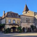 Place des Cornières à Monpazier avec arcades en pierre et clocher de l’église