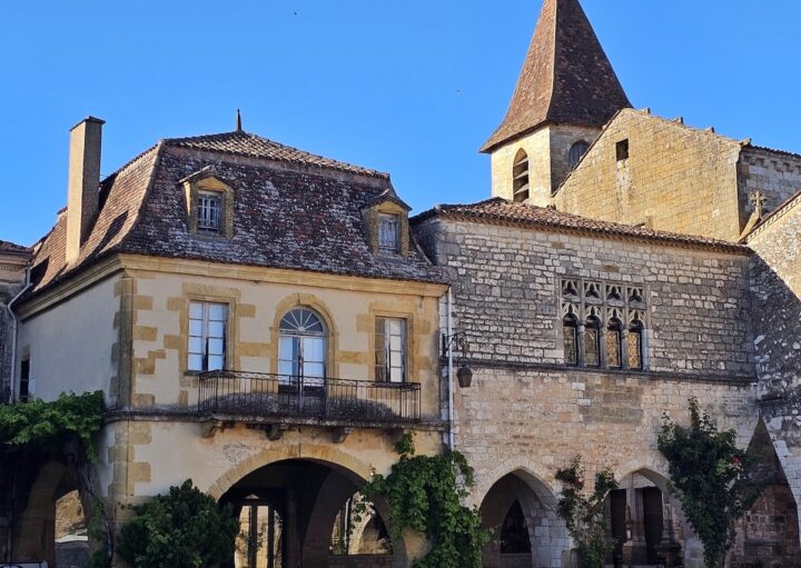 Place des Cornières à Monpazier avec arcades en pierre et clocher de l’église