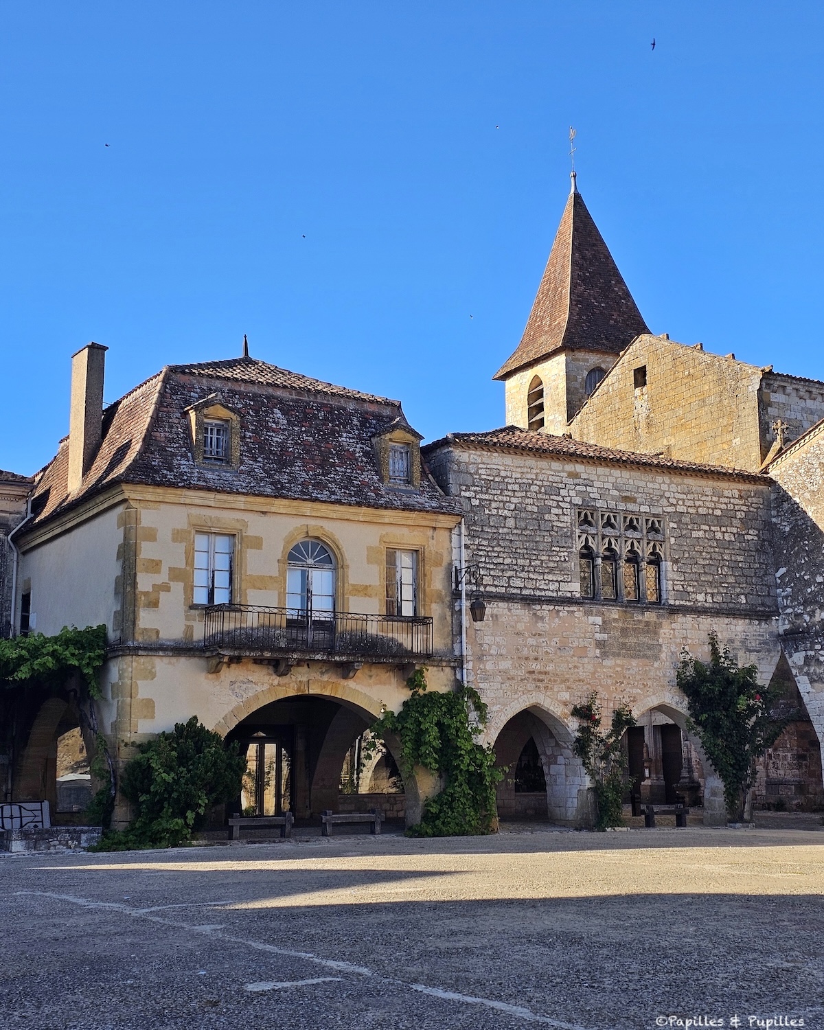 Place des Cornières à Monpazier avec arcades en pierre et clocher de l’église