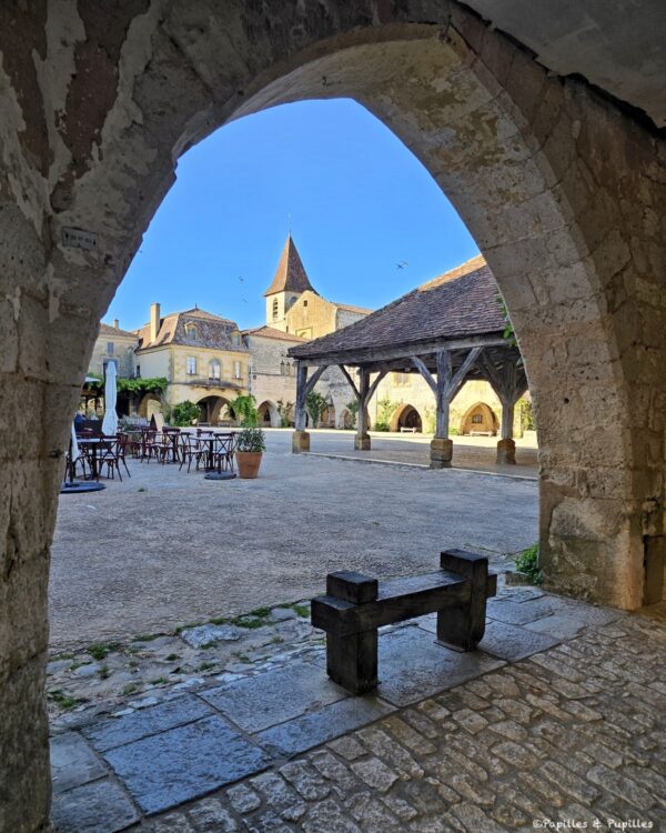 Vue de la place des Cornières à Monpazier depuis une arcade en pierre