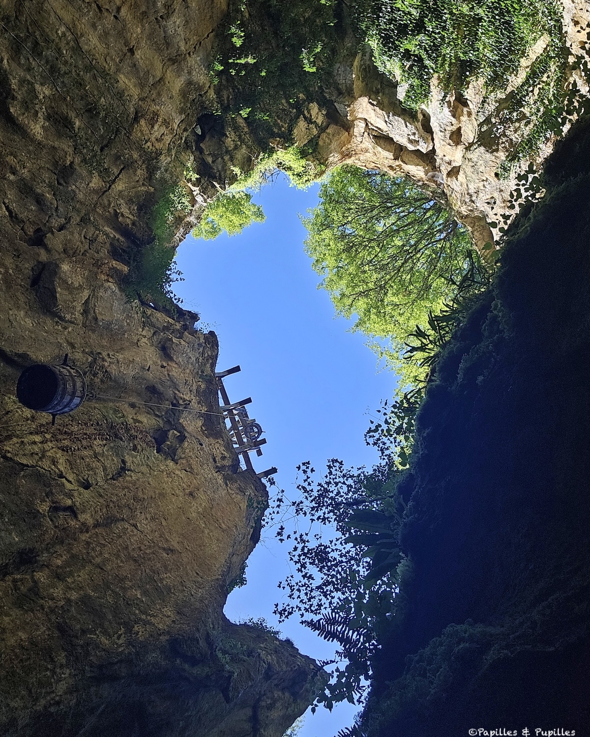 Ouverture rocheuse des Phosphatières du Cloup d’Aural avec ciel bleu et ancien treuil d’exploitation