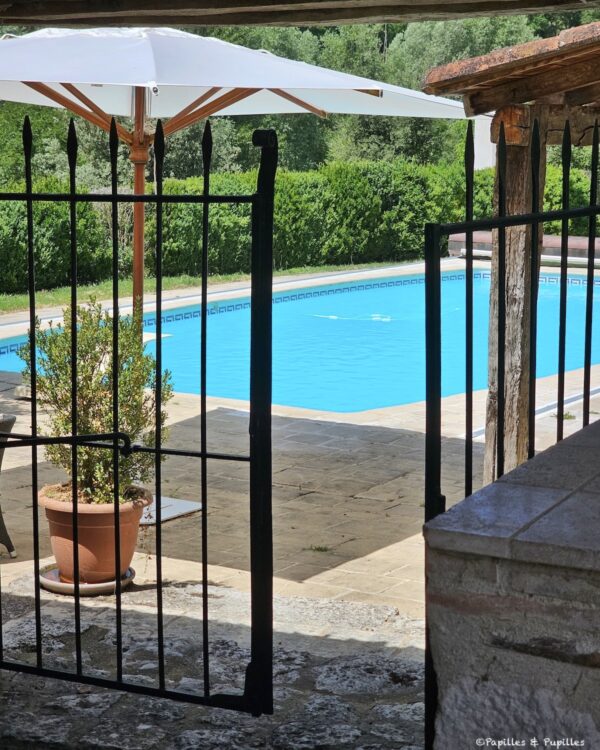 Piscine du Domaine de Saint-Géry vue depuis une grille en pierre
