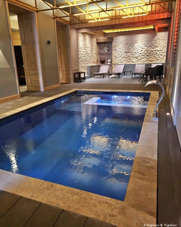 Piscine intérieure de l’hôtel Les Glycines dans un espace spa avec murs en pierre