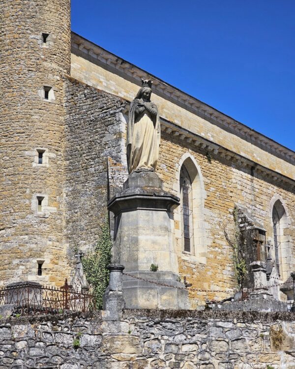 VIerge devant l’église de Puy-l’Évêque, avec murs en pierre et tour ronde