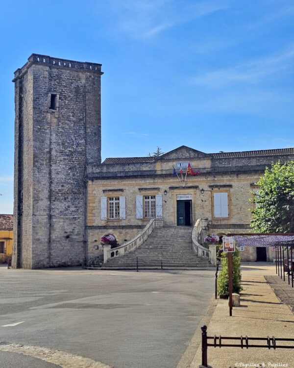 Mairie de Puy-l’Évêque avec escalier, grande tour en pierre et drapeaux
