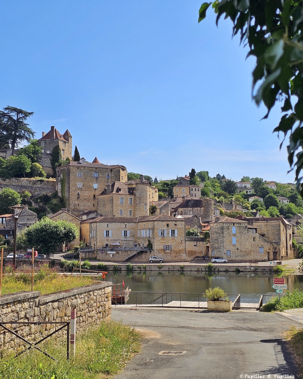 Puy-l’Évêque vu depuis les bords du Lot avec maisons anciennes, château et église en hauteur