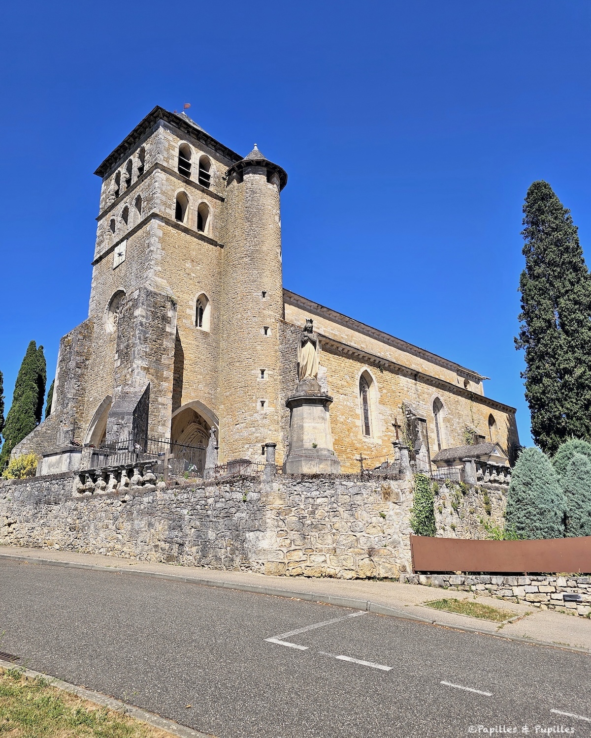 Église de Puy-l’Évêque avec son clocher, sa tour ronde et sa façade en pierre