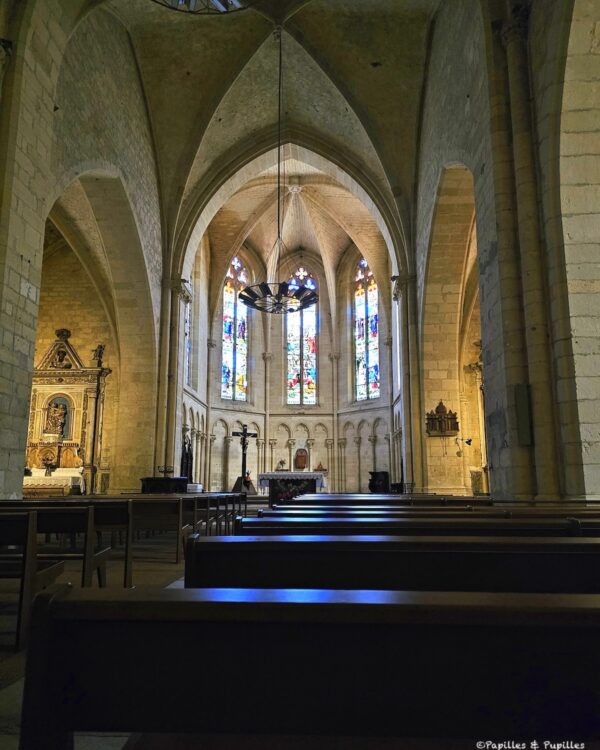 Intérieur de l’église de Puy-l’Évêque avec voûtes, vitraux et rangées de bancs