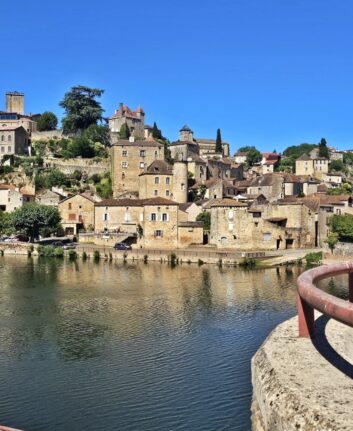 Puy-l’Évêque vu depuis les bords du Lot, avec maisons en pierre et reflets sur l’eau