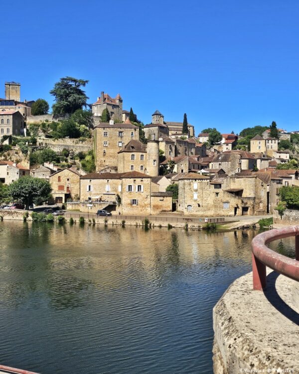 Puy-l’Évêque vu depuis les bords du Lot, avec maisons en pierre et reflets sur l’eau