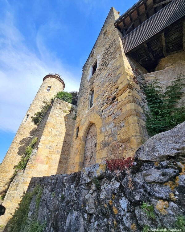 Tour ronde et façade en pierre dans une rue ancienne de Puy-l’Évêque