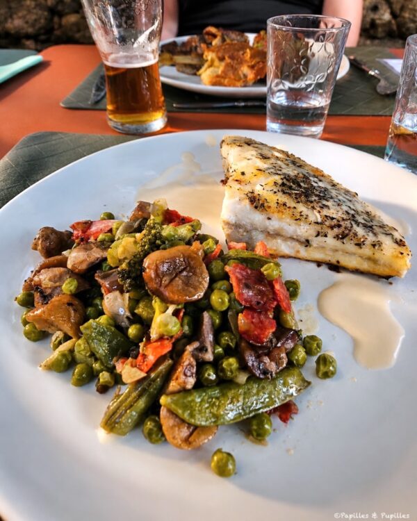 Aile de raie grillée servie avec légumes, petits pois et champignons