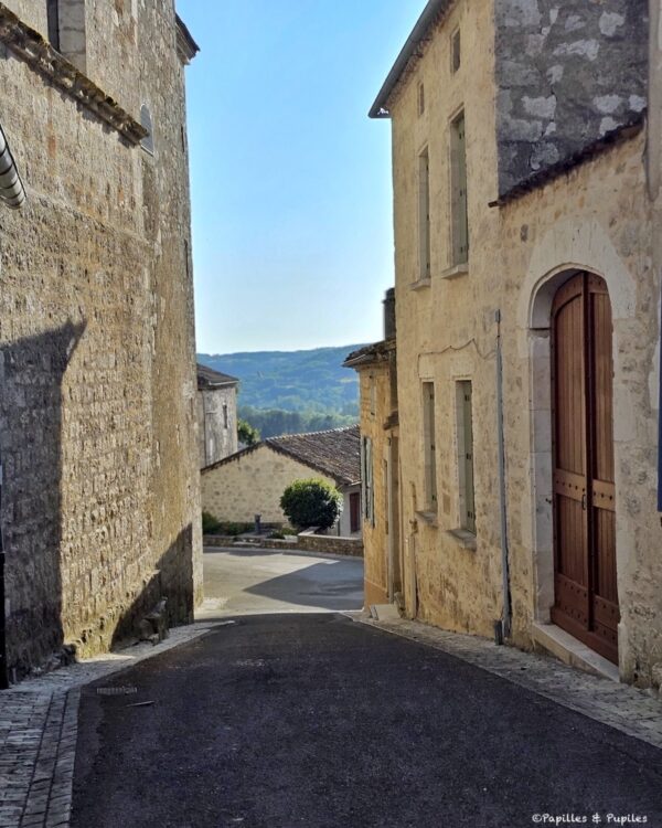 Ruelle en pente à Montcuq-en-Quercy-Blanc avec maisons en pierre et vue sur la campagne