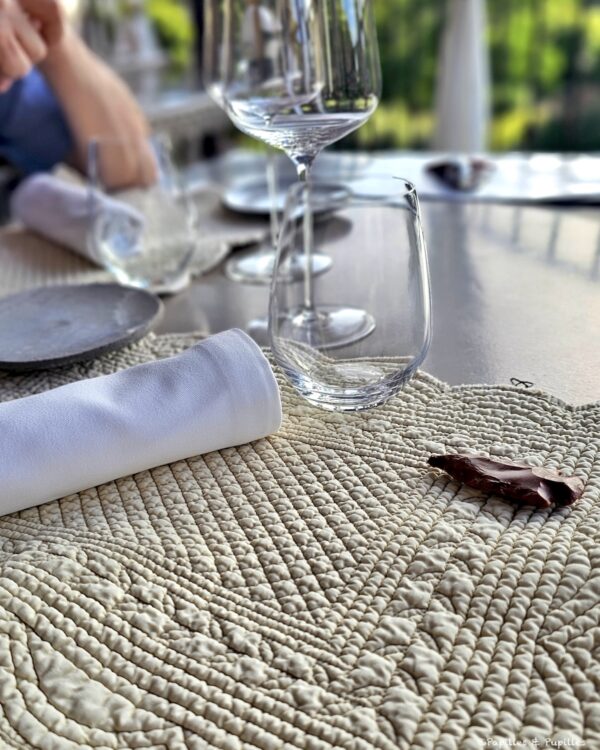 Table dressée au restaurant Le 1862 avec verres, serviette blanche et lumière sur la terrasse