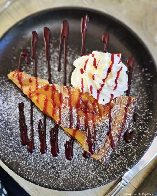 Part de tarte amandine aux abricots servie avec chantilly et coulis rouge
